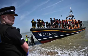 Kuter Royal National Lifeboat Institution (RNLI) z imigrantami przybija do wybrzeża Anglii niedaleko Dungeness, czerwiec 2022 r. // Fot. Ben Stansall / AFP / East News